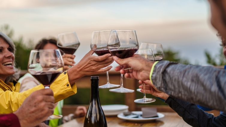 Amis souriants trinquant au vin rouge lors d'un apéritif.