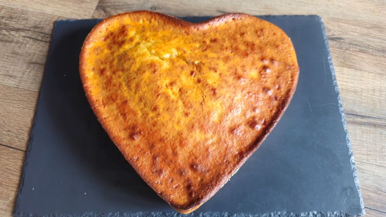 Gâteau moelleux au miel d'acacia en forme de cœur sur une ardoise.